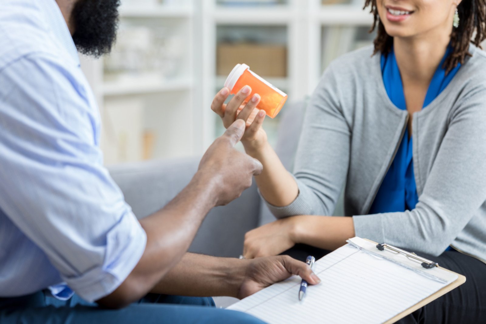 Male mental health professional explains an anti depressant medication to a female patient. The patient is holding the medication container.