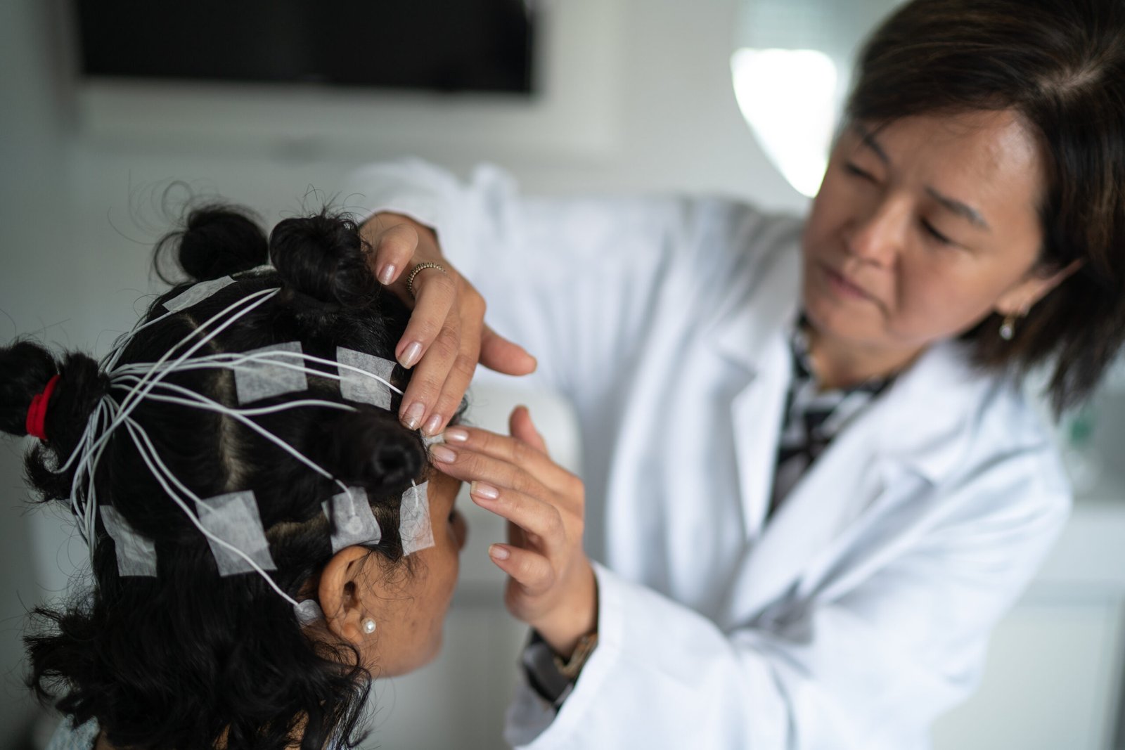Doctor placing electrodes on patient's head for a medical exam